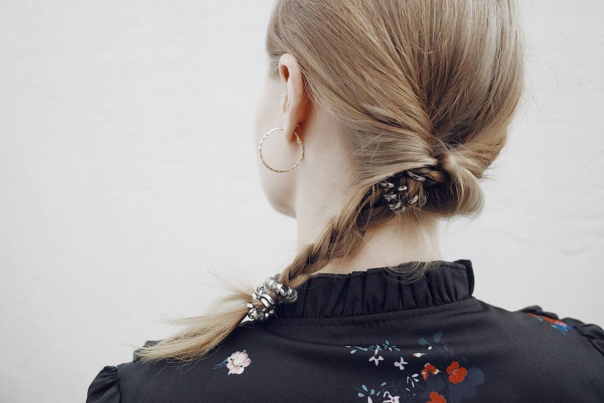 Model wearing minimalist hair loop charms on beach-ready waves with sunlit glow