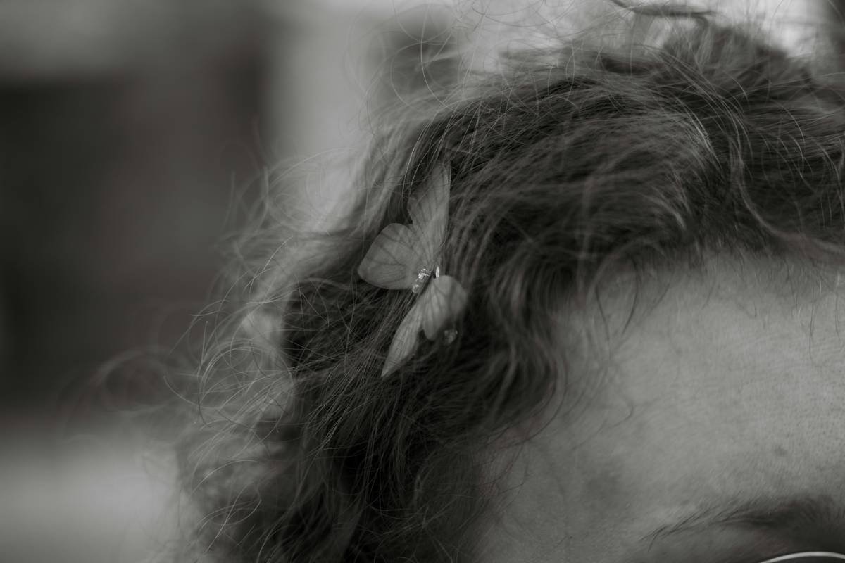 Close-up of glitter hair accents applied near hair part using tweezers