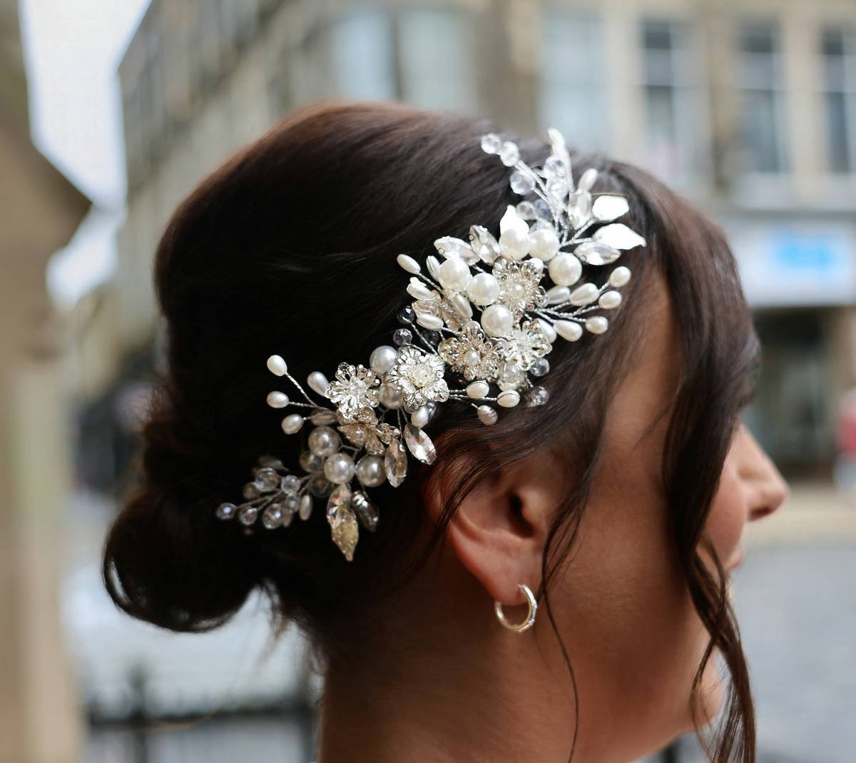 Close-up of hand threading hair loop charms onto a satin scrunchie with healthy hair strands